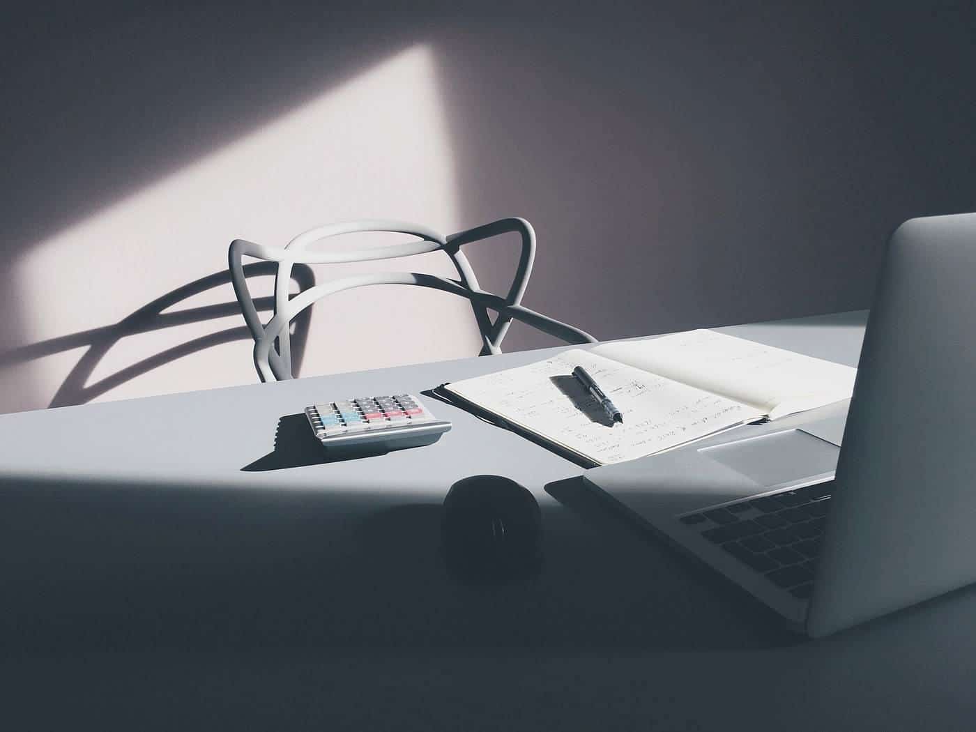 A laptop computer on a desk beside a calculator