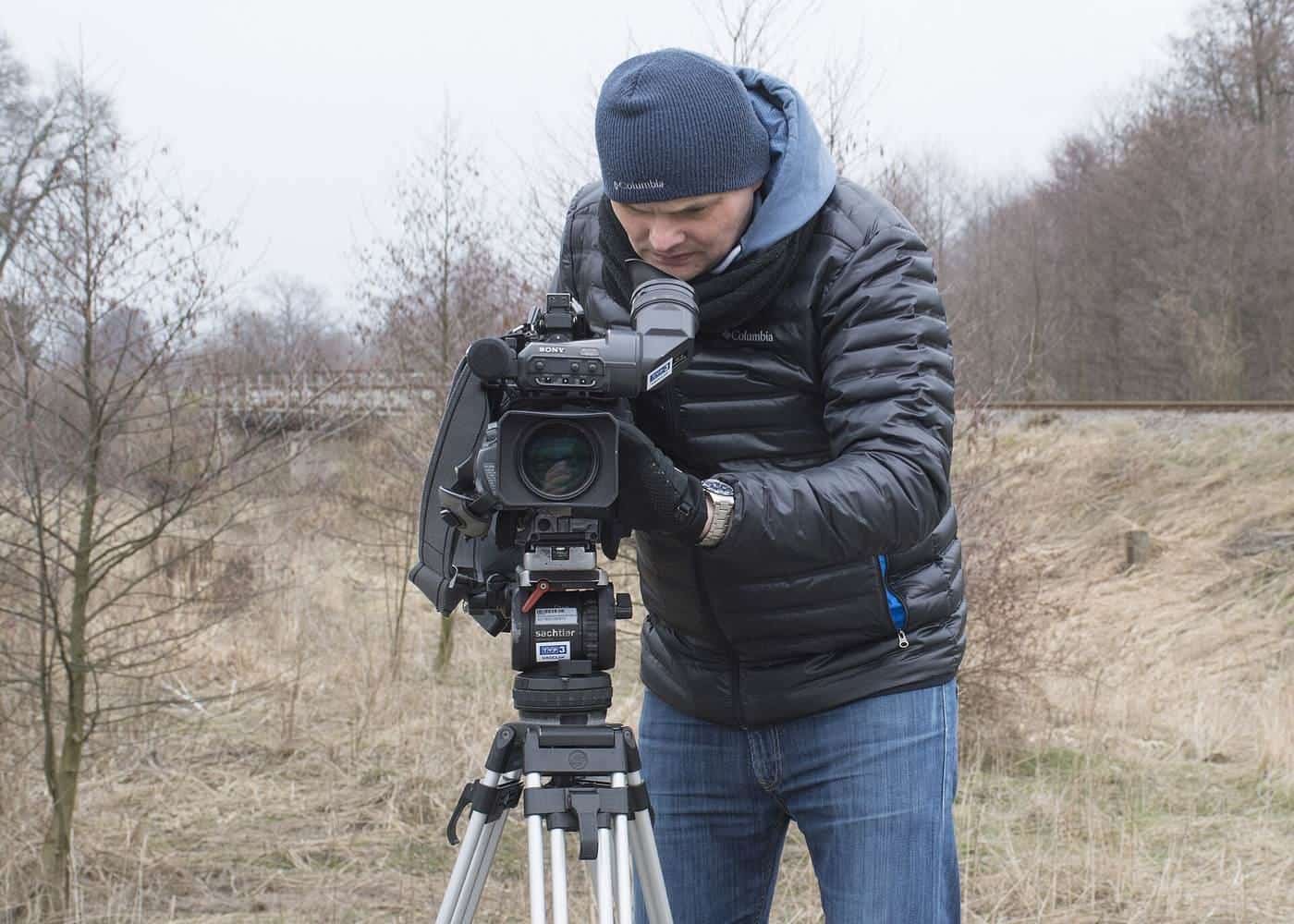 A camera operator filming with a professional video camera