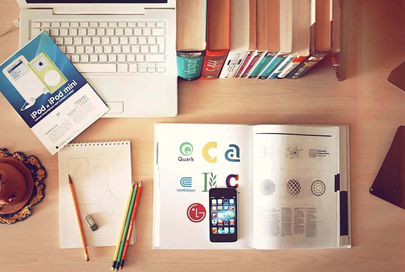 A laptop, phone and notebooks on a desk